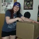 A plump, redheaded girl wearing glasses repeatedly farts into a cardboard box. About 6.5 minutes.